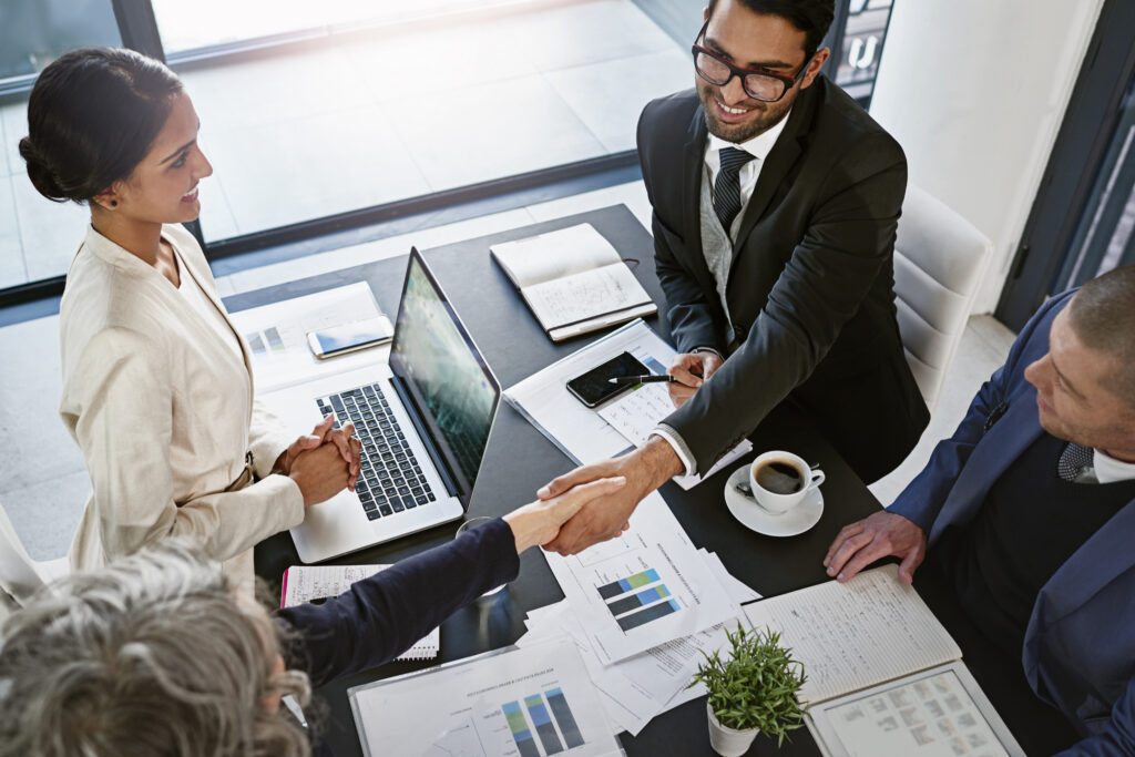 Sales reps shaking hands with a client, showing a successful client acquisition.